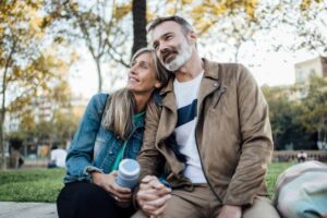 A middle-aged couple sitting close and smiling at a park, reflecting the warmth and emotional connection sparked by their shared love for fine art. 