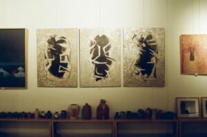 A curated wall display of contemporary African paintings and handcrafted pottery at Ovico Gallery, showcasing abstract art inspired by African culture and storytelling.