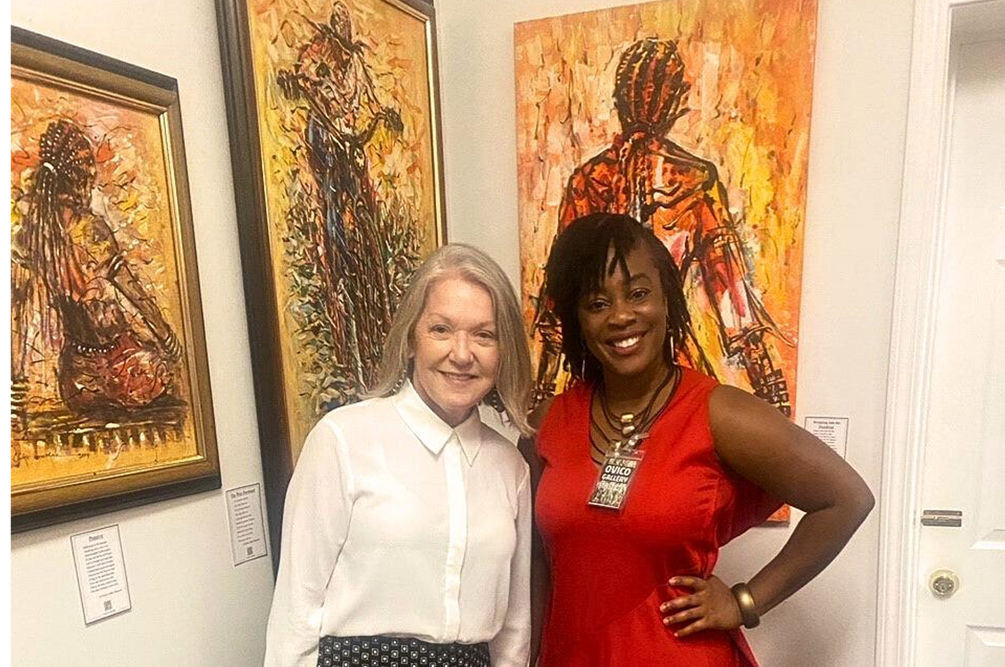 Two women standing in front of expressive African paintings at Ovico Gallery, showcasing vibrant brushwork and storytelling through art and culture.