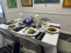 An intimate dining experience set inside an art gallery in St. Augustine, with African contemporary paintings, refined table décor, and a quiet gallery ambiance at Ovico Gallery.